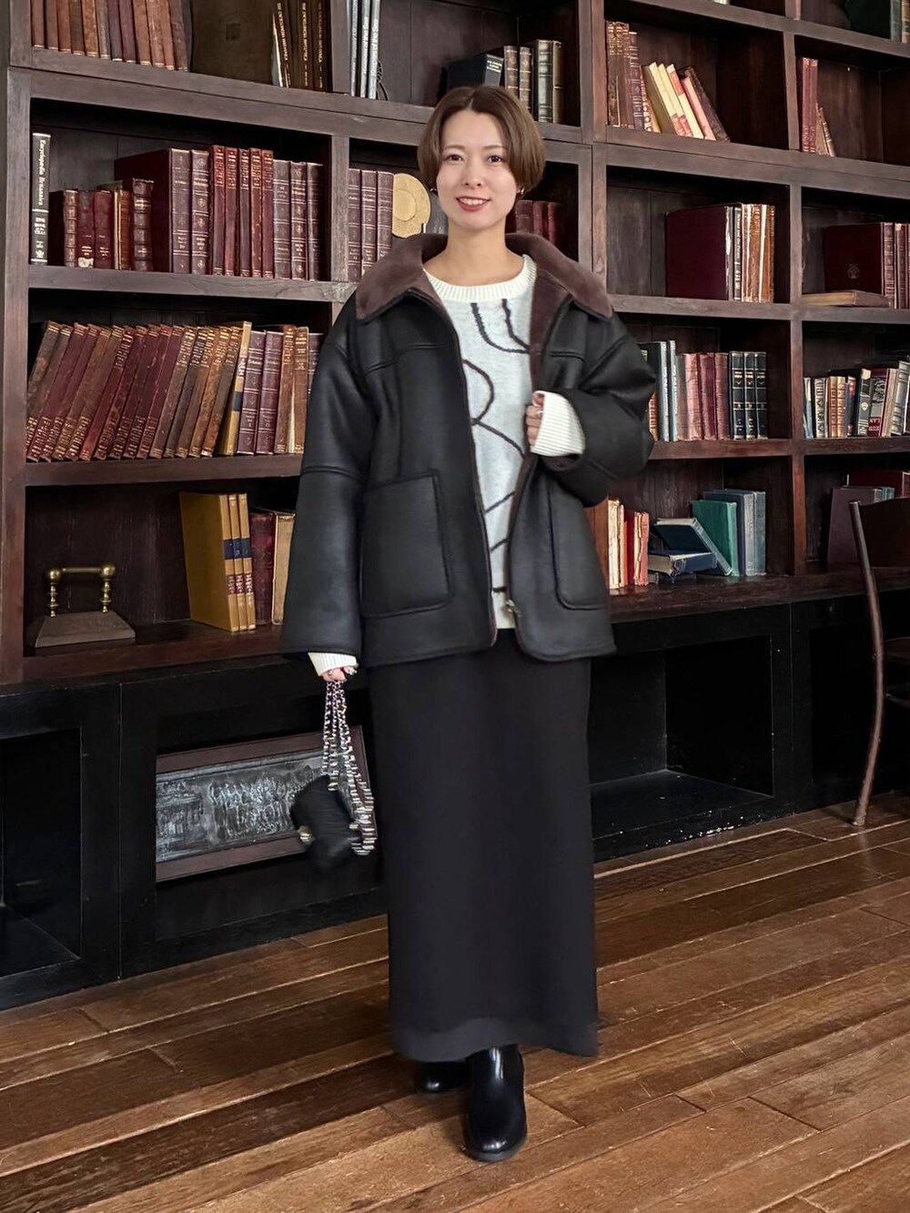 ホワイト系のニット/セーター、ブラック系のブルゾン、ブラック系のブーツを着用したレディースの秋コーディネートの4枚目の写真