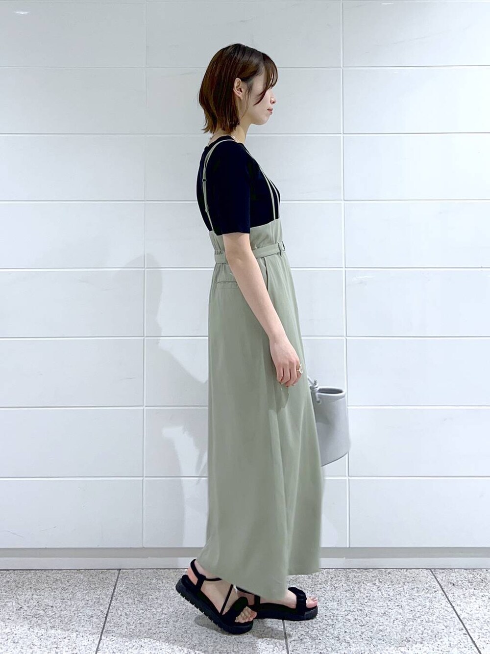 グリーン系のスカート、ブラック系のニット/セーター、ブラック系のサンダルを着用したレディースの春コーディネートの2枚目の写真