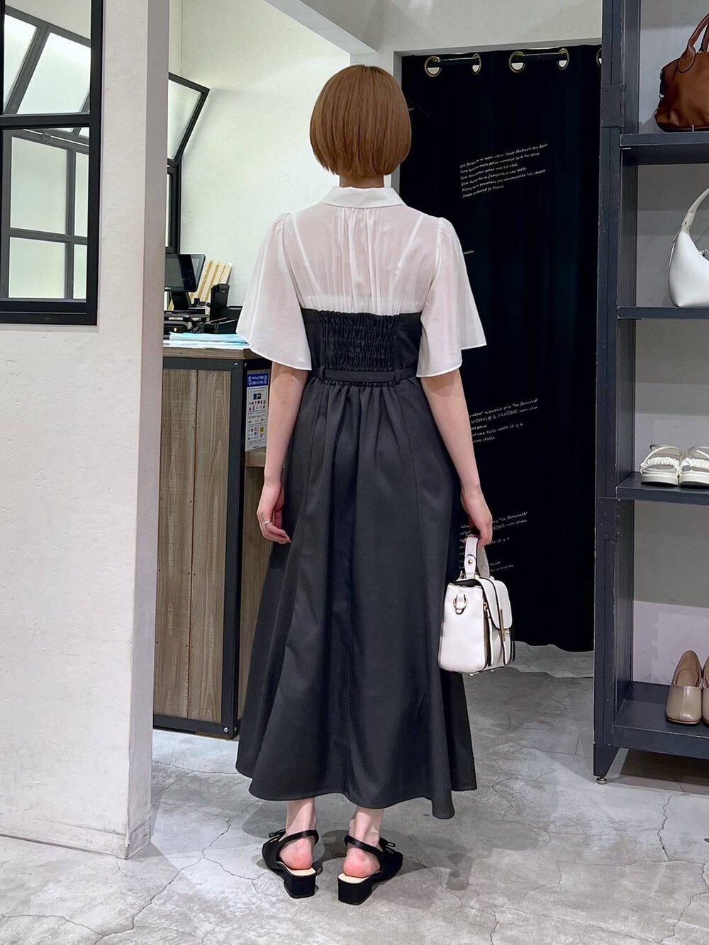 ブラック系のサンダル、グレー系のワンピース、ホワイト系のショルダーバッグを着用したレディースの春コーディネートの4枚目の写真