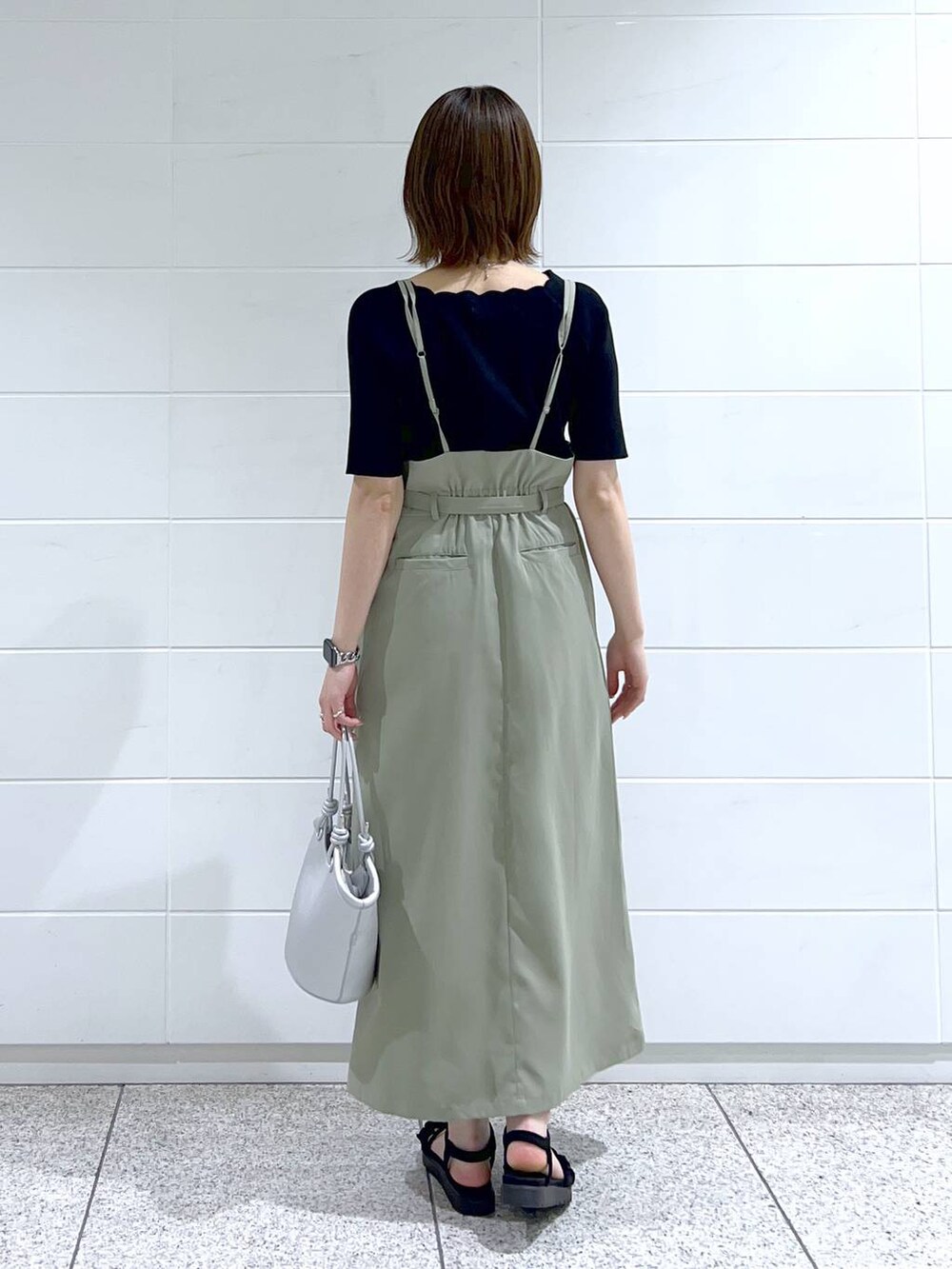 グリーン系のスカート、ブラック系のニット/セーター、ブラック系のサンダルを着用したレディースの春コーディネートの3枚目の写真