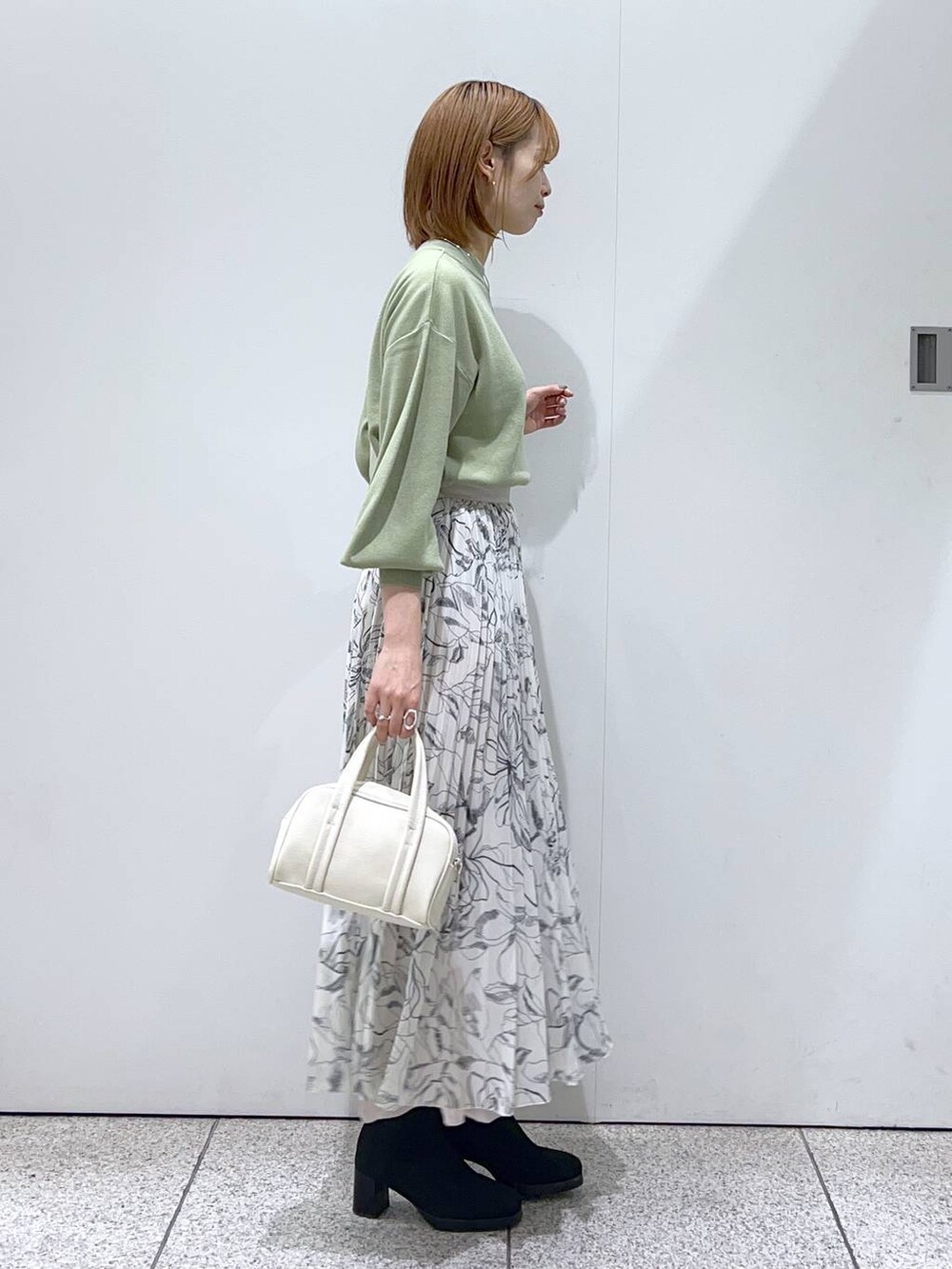 ホワイト系のブルゾン、ホワイト系のボストンバッグ、ブラック系のブーツを着用したレディースの秋コーディネートの5枚目の写真