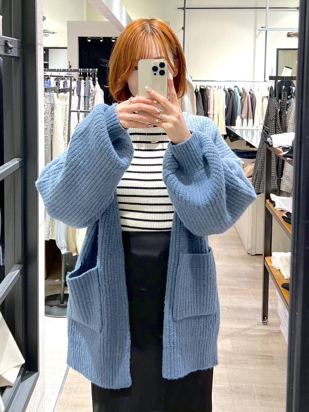 ブラック系のブーツ、ブラック系のスカート、ホワイト系のニット/セーターを着用したレディースの秋コーディネートの4枚目の写真