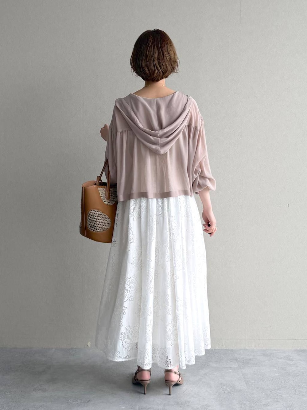 ベージュ系のパーカー、ブラウン系のトートバッグ、ホワイト系のワンピースを着用したレディースの春コーディネートの3枚目の写真