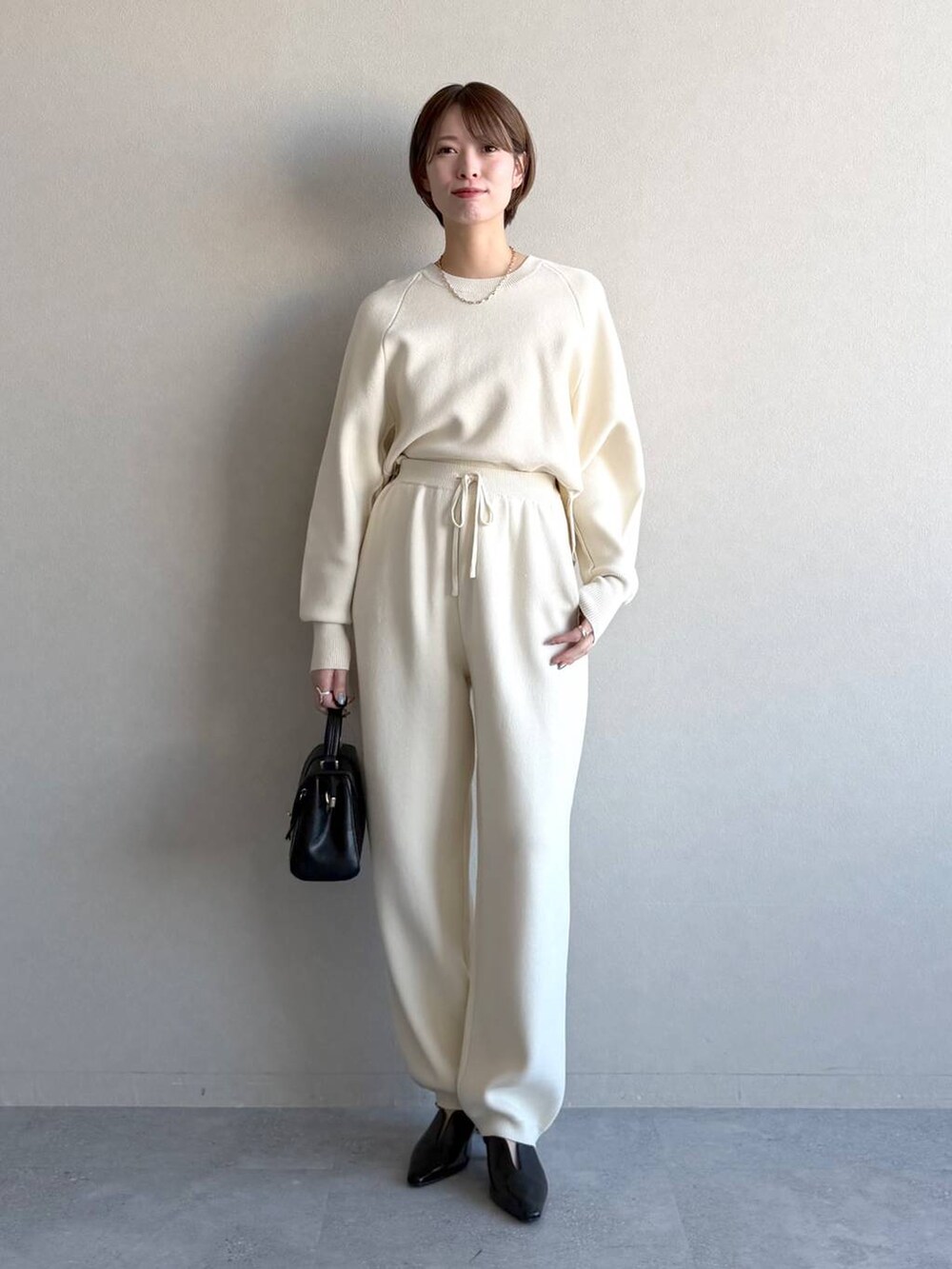 ブラック系のショルダーバッグ、ブラック系のサンダル、グレー系のニット/セーターを着用したレディースの冬コーディネートの5枚目の写真