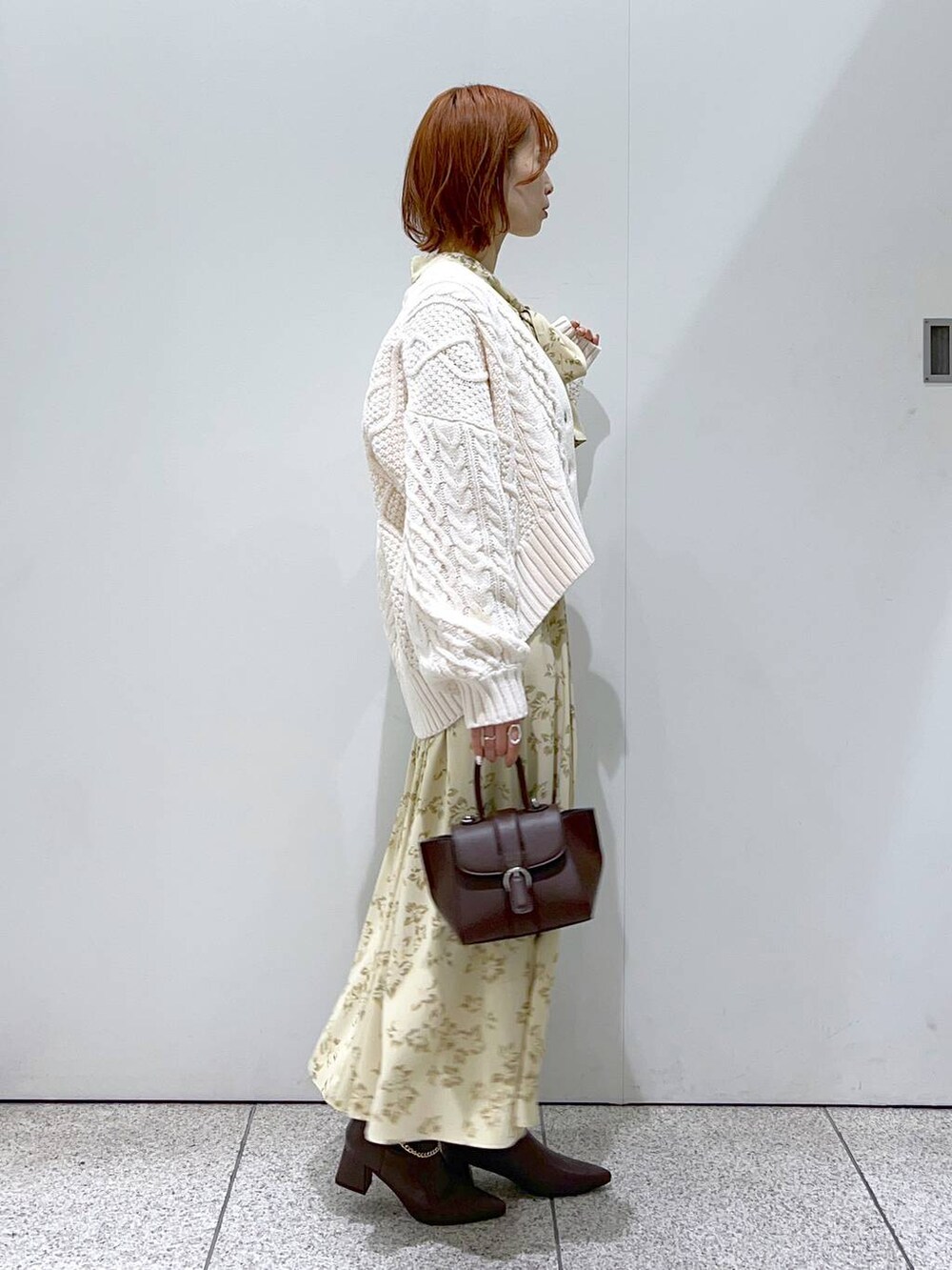 ブラウン系のハンドバッグ、ベージュ系のワンピース、ホワイト系のカーディガン/ボレロを着用したレディースの秋コーディネートの2枚目の写真