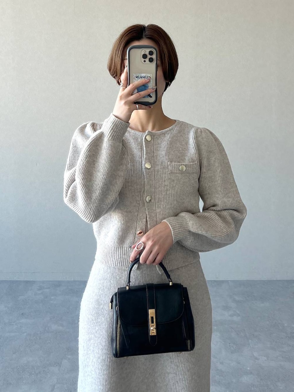 ブラック系のブーツ、ブラック系のショルダーバッグ、ホワイト系のワンピースを着用したレディースの冬コーディネートの4枚目の写真