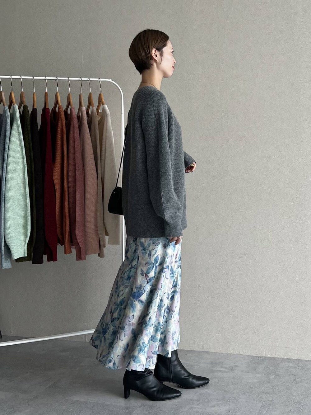 ホワイト系のスカート、ブラック系のショルダーバッグ、グレー系のニット/セーターを着用したレディースの秋コーディネートの2枚目の写真