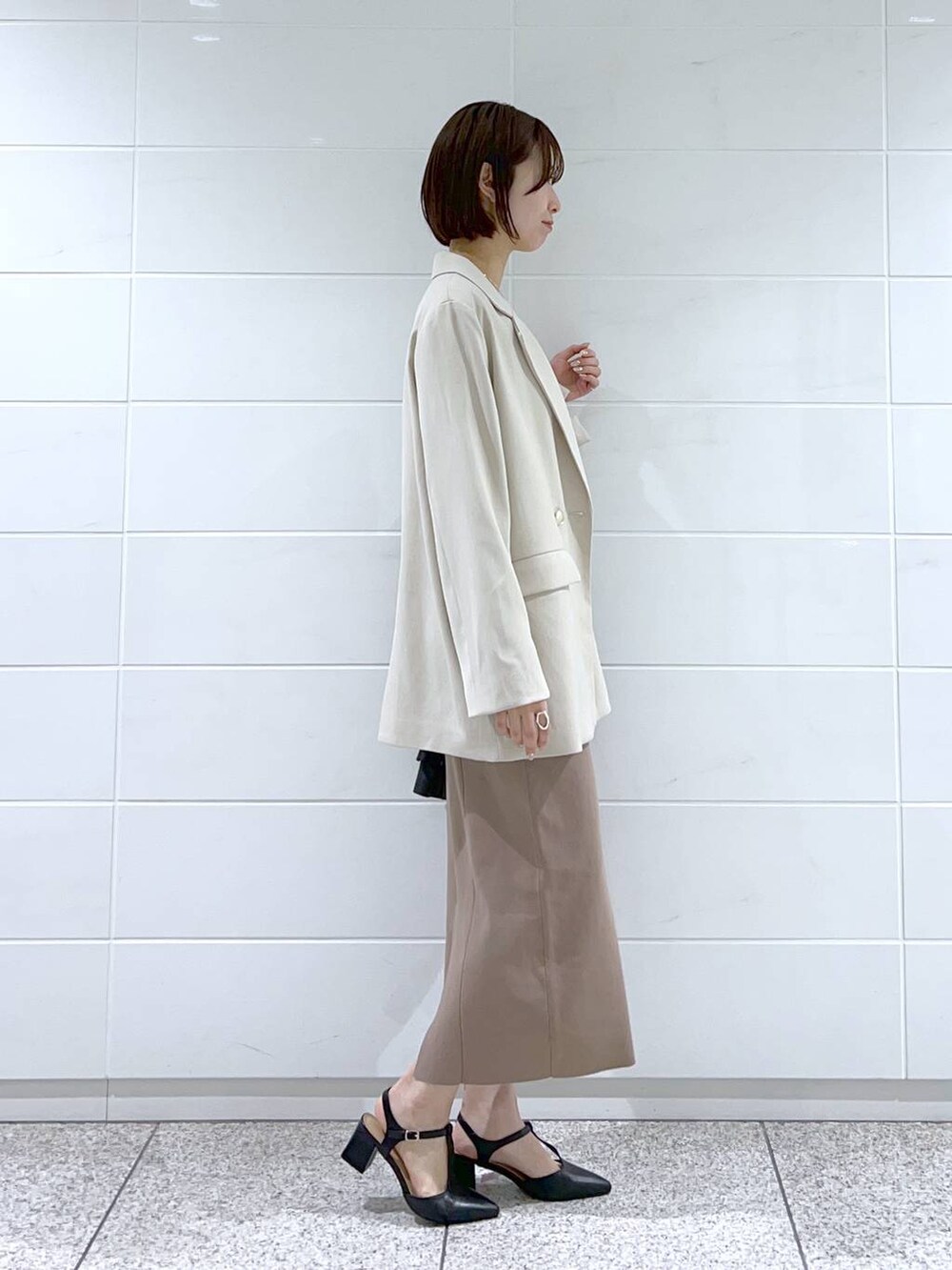 ホワイト系のテーラードジャケット、ブラック系のパンプス、ブラック系のトートバッグを着用したレディースの冬コーディネートの2枚目の写真