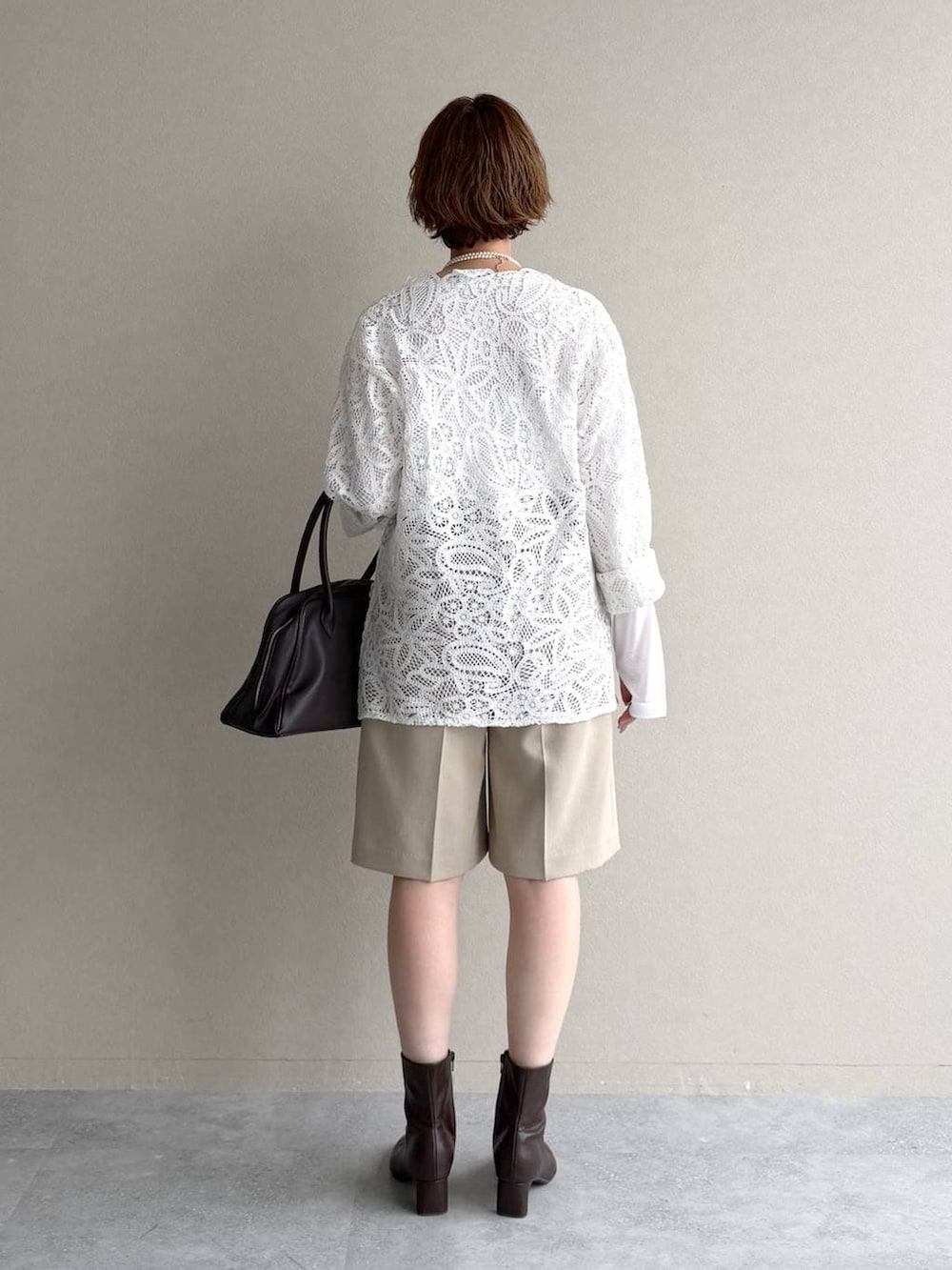 ホワイト系のTシャツ/カットソー、ブラウン系のブーツ、ブラウン系のトートバッグを着用したレディースの冬コーディネートの3枚目の写真