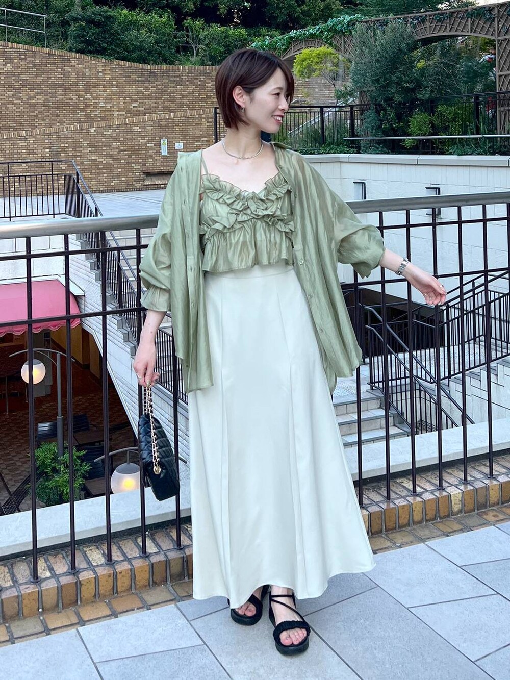 ブラック系のサンダル、ブラック系のショルダーバッグ、ホワイト系のスカートを着用したレディースの夏コーディネートの2枚目の写真