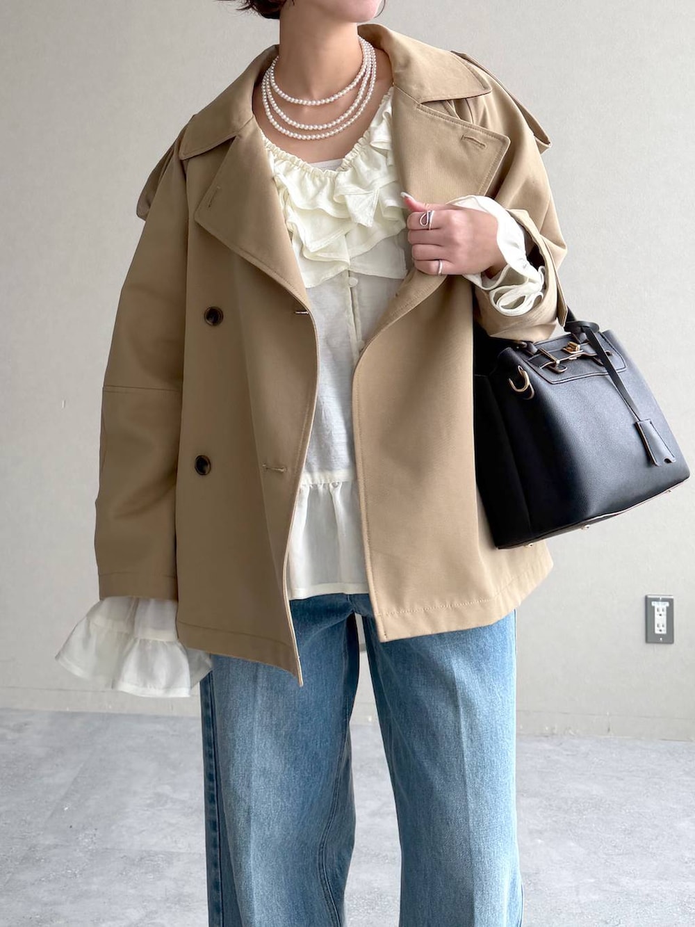 ブラック系のサンダル、ベージュ系のトレンチコート、ブルー系のデニムパンツを着用したレディースの春コーディネートの5枚目の写真