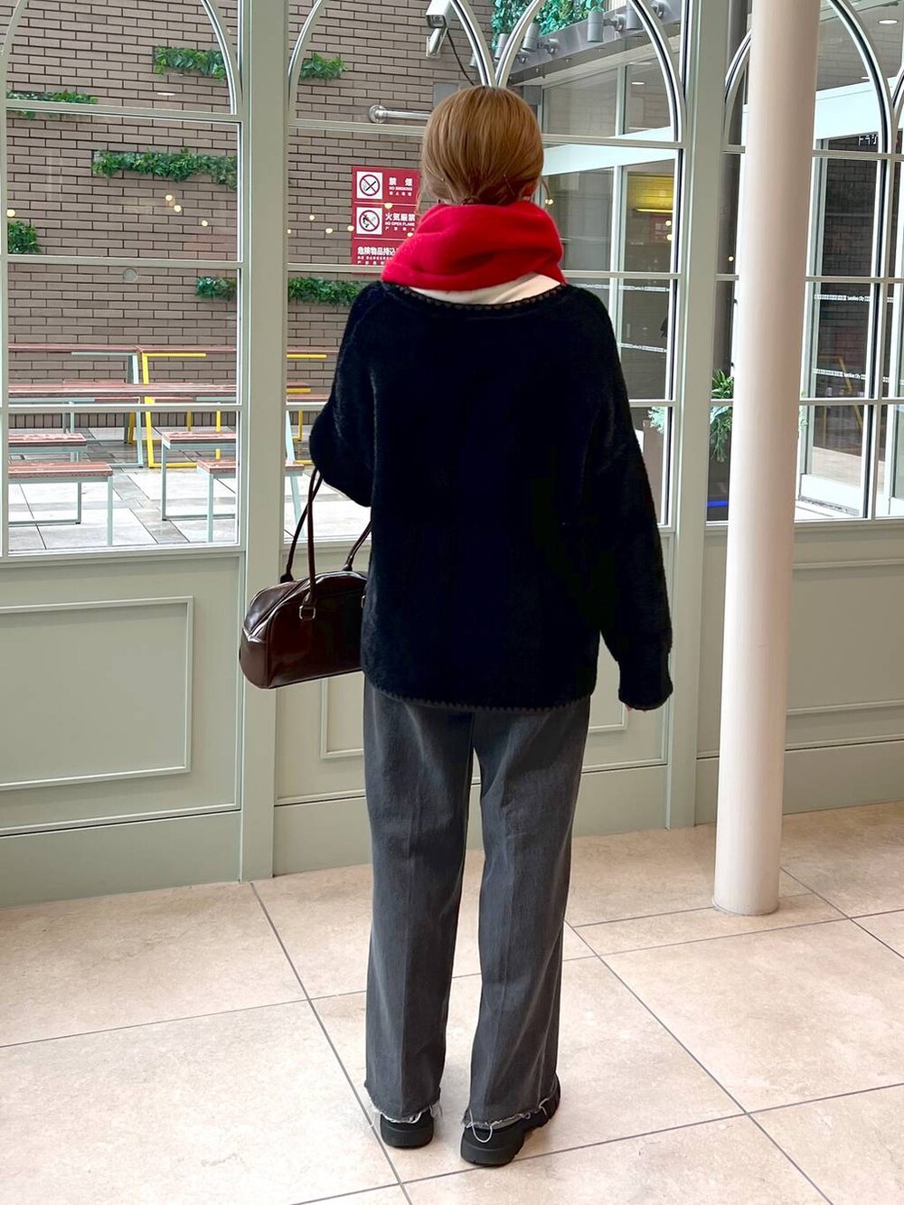 ブラック系のデニムパンツ、ブラック系のブーツ、ブラウン系のハンドバッグを着用したレディースの秋コーディネートの3枚目の写真