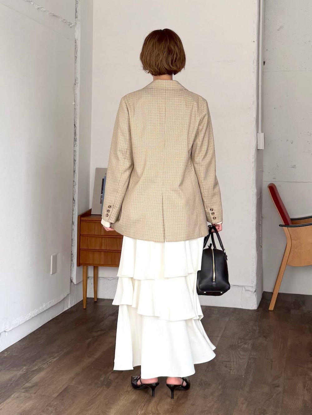 ブラック系のハンドバッグ、ベージュ系のテーラードジャケット、ホワイト系のスカートを着用したレディースの春コーディネートの3枚目の写真