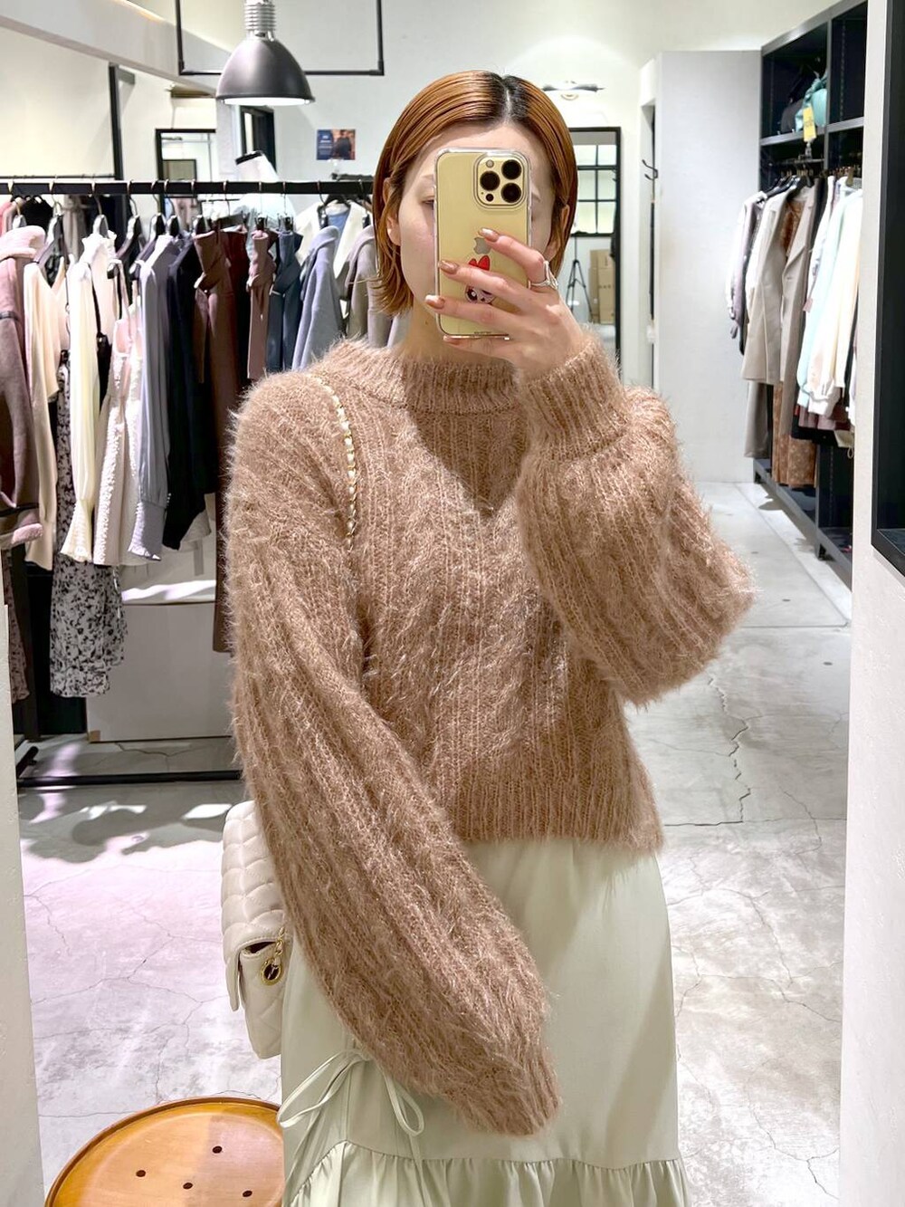 ホワイト系のショルダーバッグ、ブラウン系のブーツ、ブラウン系のニット/セーターを着用したレディースの冬コーディネートの4枚目の写真