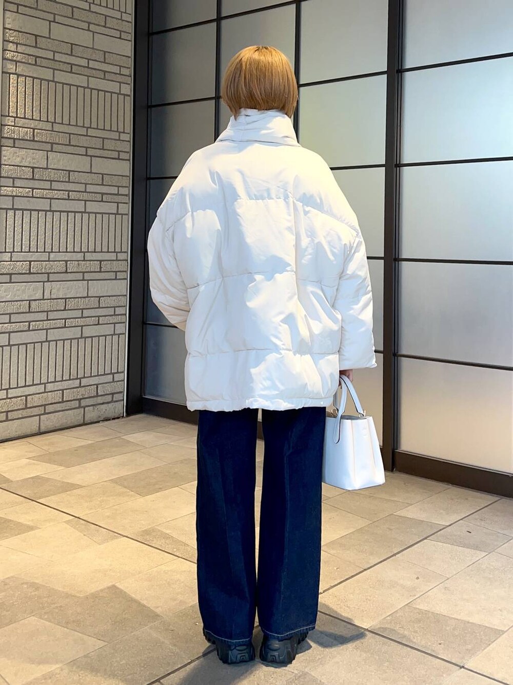 ホワイト系のブルゾン、ホワイト系のショルダーバッグ、ブルー系のスラックスを着用したレディースの冬コーディネートの3枚目の写真