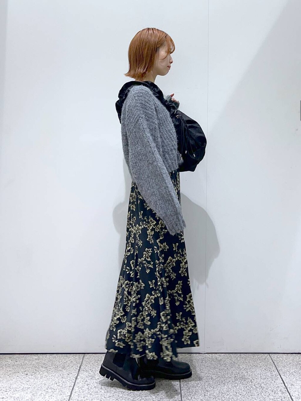 ブラック系のハンドバッグ、ブラック系のブーツ、ブラック系のスカートを着用したレディースの秋コーディネートの2枚目の写真