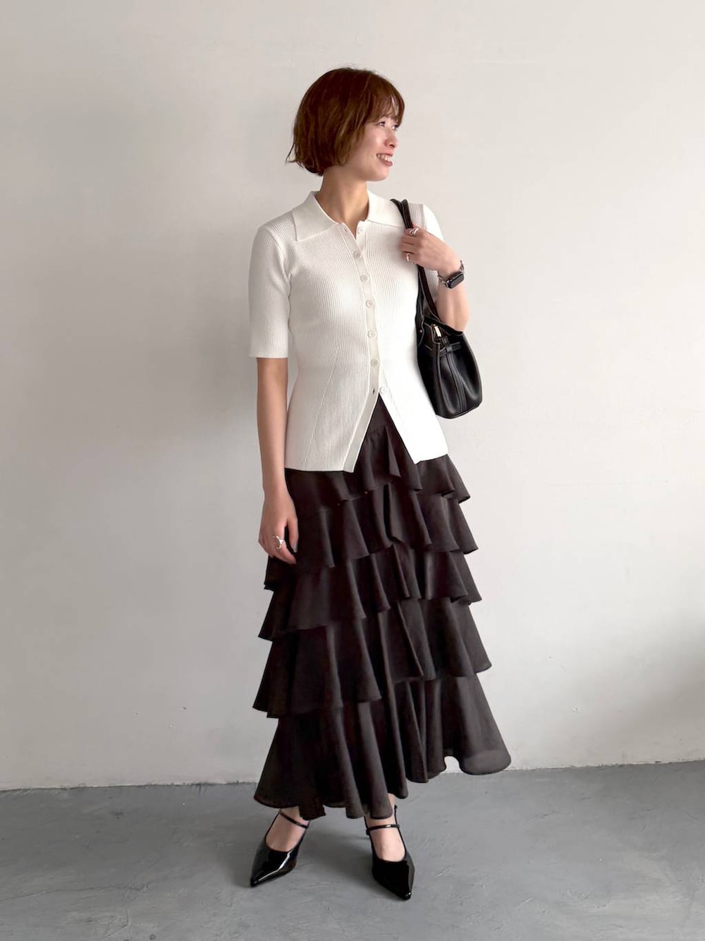 ブラック系のサンダル、ホワイト系のカーディガン/ボレロ、ブラック系のスカートを着用したレディースの春コーディネートの6枚目の写真