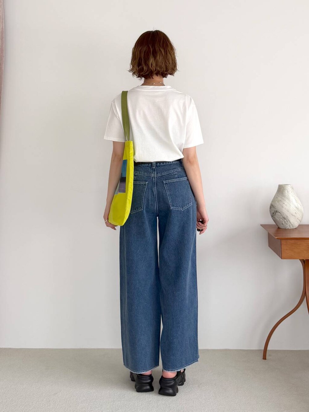ブルー系のデニムパンツ、ブラック系のサンダル、ブラック系のベルトを着用したレディースの春コーディネートの3枚目の写真