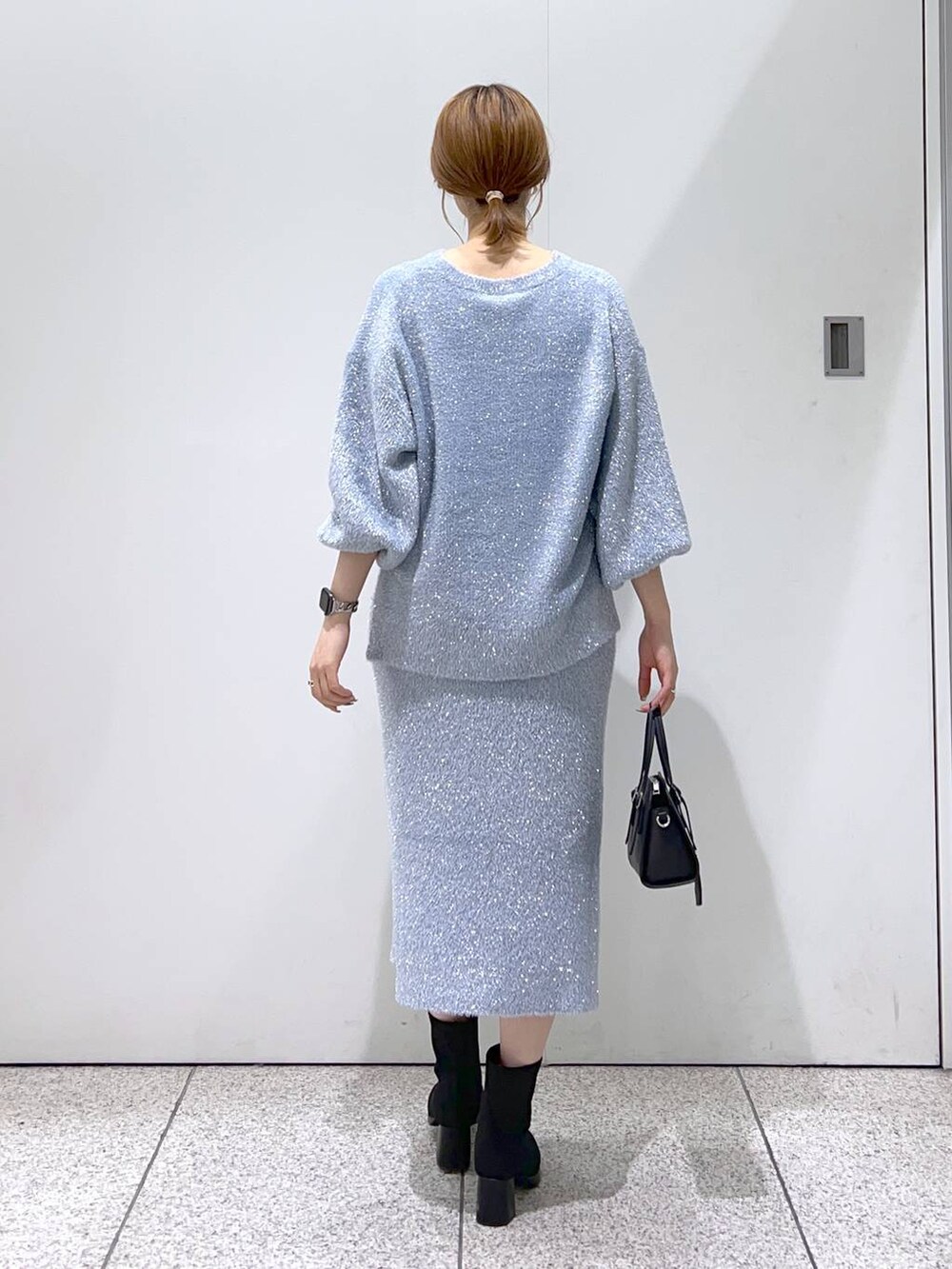 ブラック系のボストンバッグ、ブラック系のブーツ、ブルー系のニット/セーターを着用したレディースの秋コーディネートの3枚目の写真