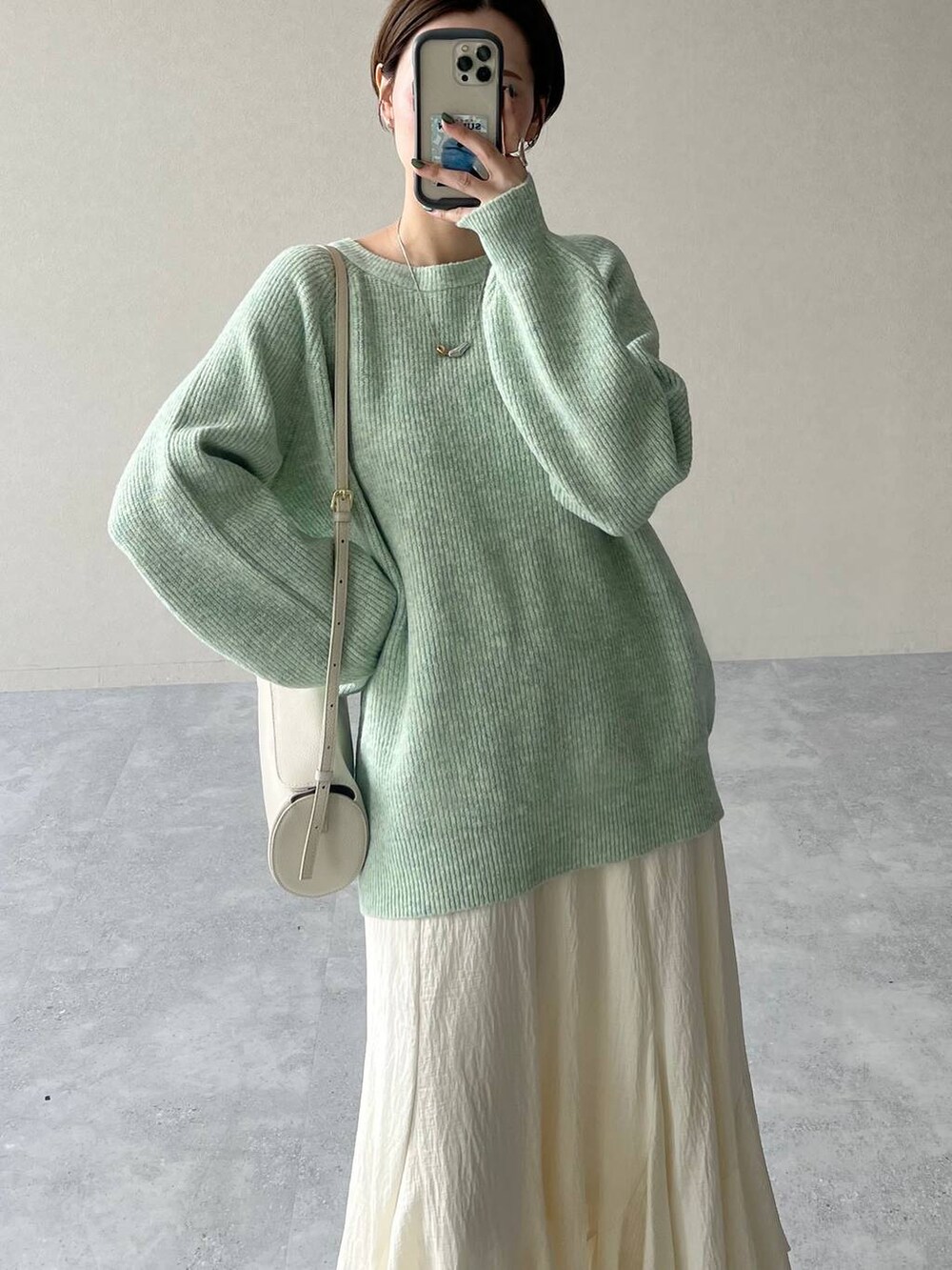 ホワイト系のスカート、ブラック系のブルゾン、ホワイト系のショルダーバッグを着用したレディースの秋コーディネートの8枚目の写真