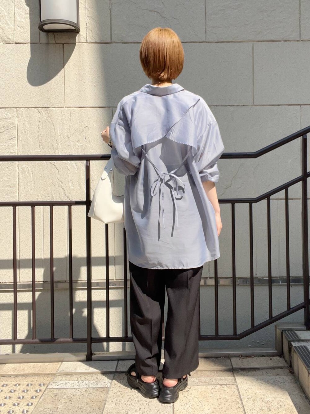 ブラック系のサンダル、ホワイト系のショルダーバッグ、ブラック系のスラックスを着用したレディースの夏コーディネートの3枚目の写真