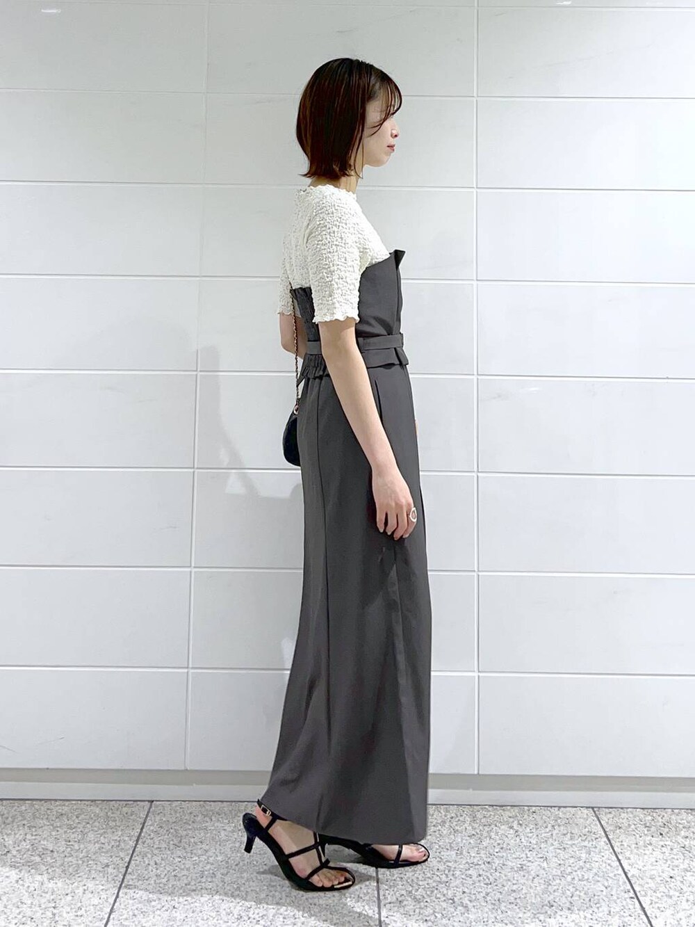 グレー系のスカート、ホワイト系のTシャツ/カットソー、ブラック系のショルダーバッグを着用したレディースの春コーディネートの3枚目の写真