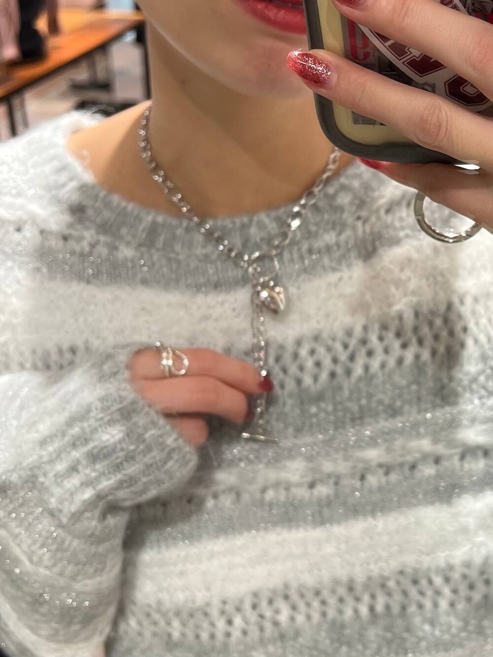 シルバー系のショルダーバッグ、ブラック系のブーツ、ブラック系のスカートを着用したレディースの冬コーディネートの5枚目の写真