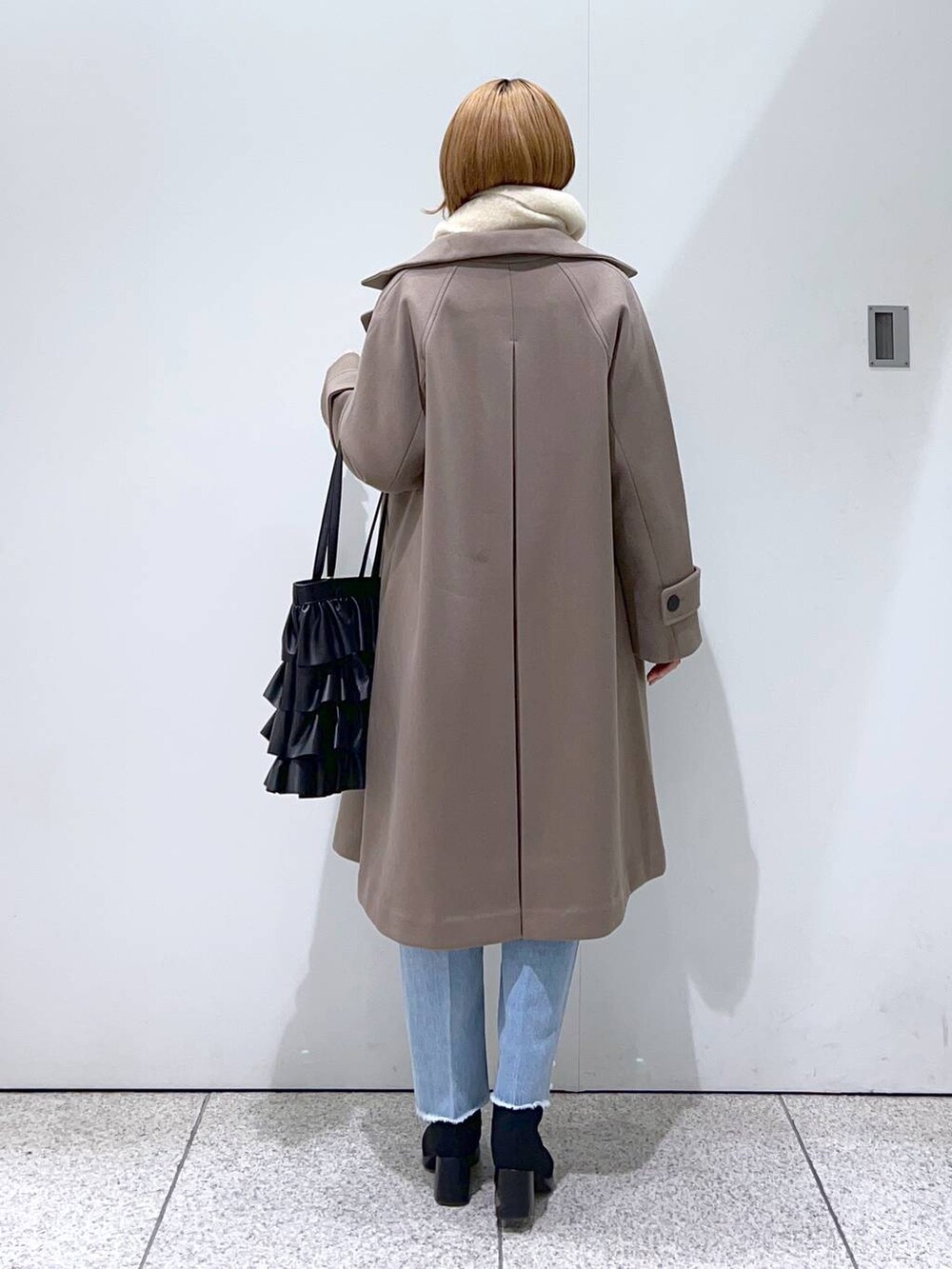 ホワイト系のニット/セーター、ブラウン系のチェスターコート、ブラック系のブーツを着用したレディースの冬コーディネートの3枚目の写真