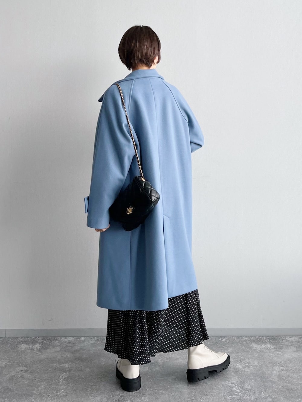 ホワイト系のニット/セーター、ブラック系のスカート、ホワイト系のブーツを着用したレディースの夏コーディネートの2枚目の写真