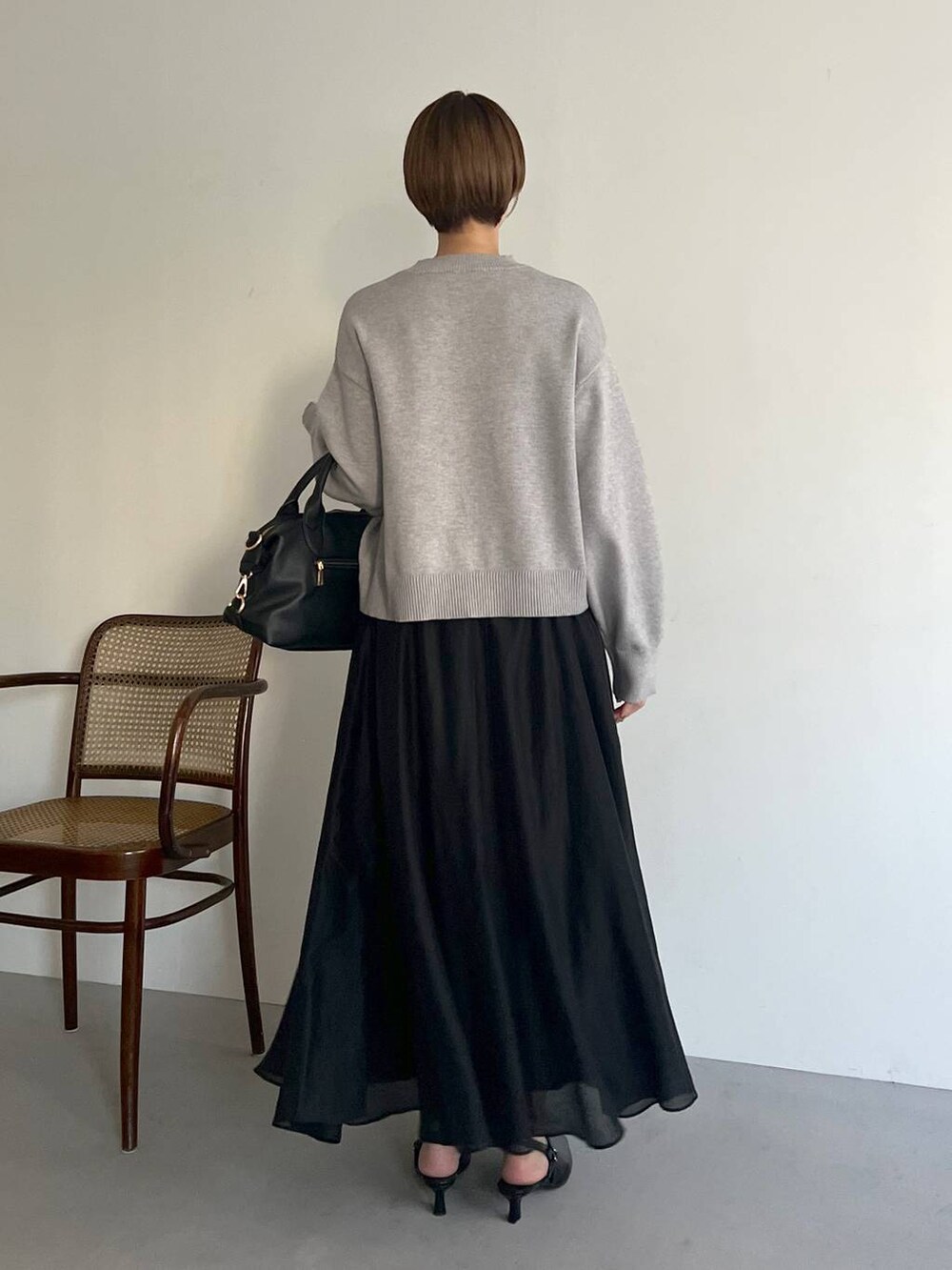 ブラック系のボストンバッグ、ブラック系のサンダル、グレー系のニット/セーターを着用したレディースの冬コーディネートの3枚目の写真