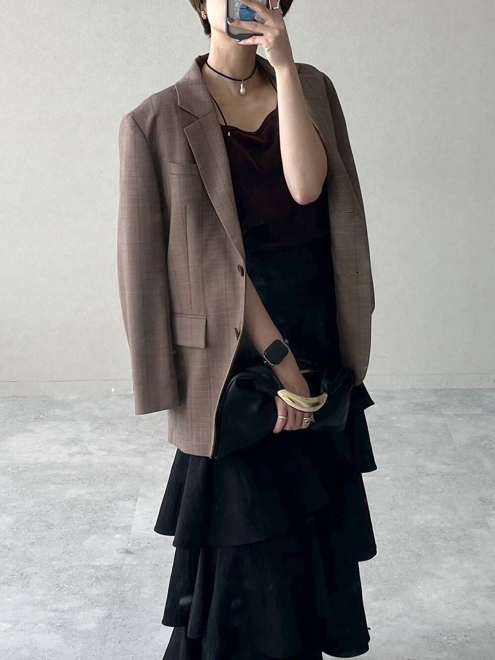 ブラック系のハンドバッグ、ベージュ系のテーラードジャケット、ブラック系のスカートを着用したレディースの秋コーディネートの3枚目の写真