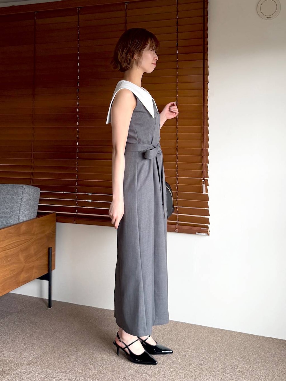 ブラック系のハンドバッグ、ブラック系のサンダル、グレー系のワンピースを着用したレディースの春コーディネートの2枚目の写真