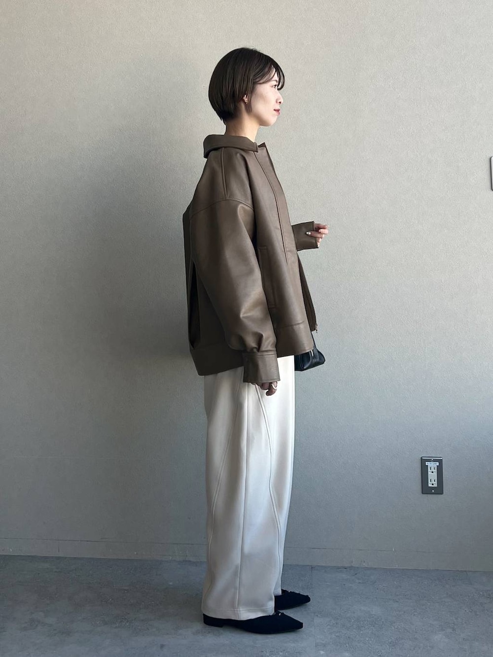 ブラック系のトートバッグ、ホワイト系のカーディガン/ボレロ、ブラック系のパンプスを着用したレディースの冬コーディネートの2枚目の写真