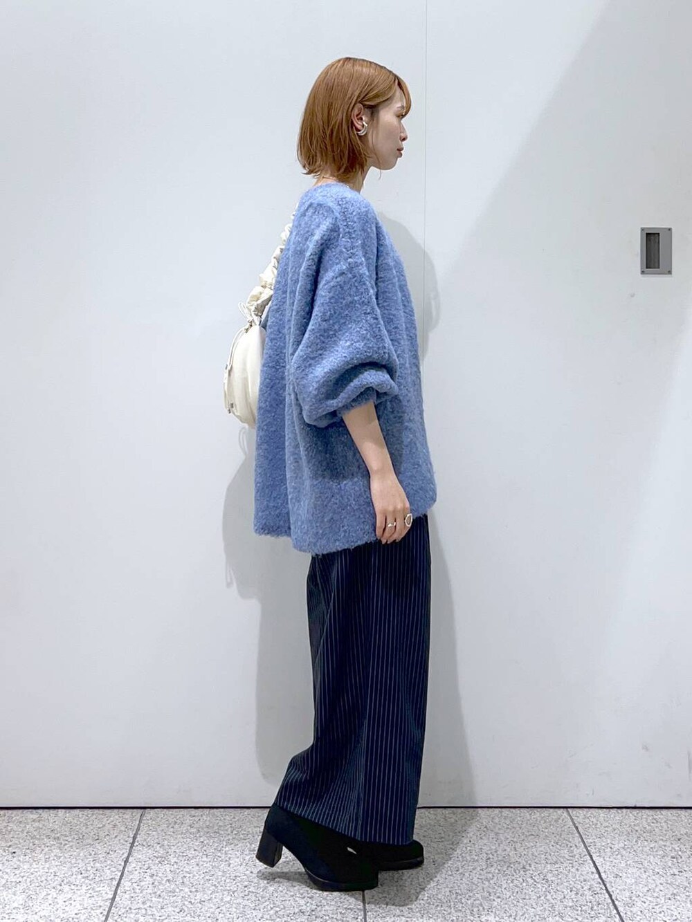 ホワイト系のタンクトップ、ホワイト系のハンドバッグ、ブラック系のブーツを着用したレディースの秋コーディネートの2枚目の写真