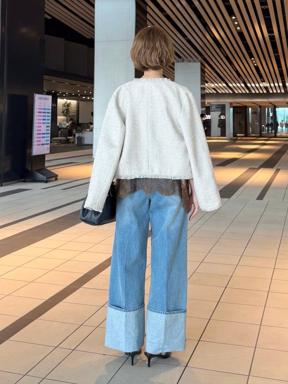 ブラック系のサンダル、ブラウン系のキャミソール、ホワイト系のノーカラージャケットを着用したレディースの春コーディネートの3枚目の写真