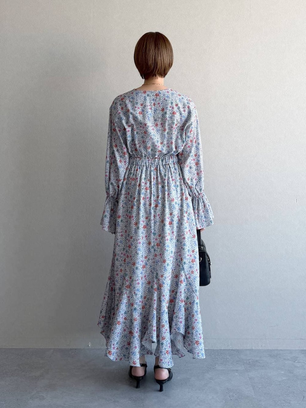 ブラック系のショルダーバッグ、ブラック系のサンダル、ブルー系のトレンチコートを着用したレディースの冬コーディネートの6枚目の写真