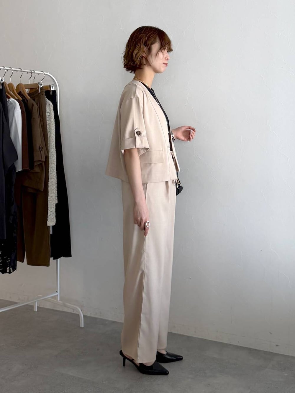 ブラック系のボストンバッグ、ブラック系のサンダル、ホワイト系のセットアップを着用したレディースの春コーディネートの2枚目の写真