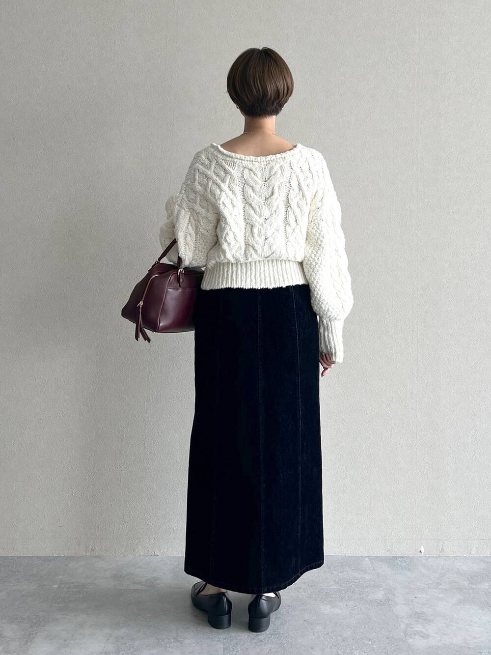 レッド系のハンドバッグ、ブラック系のスカート、ブラック系のローファーを着用したレディースの秋コーディネートの6枚目の写真