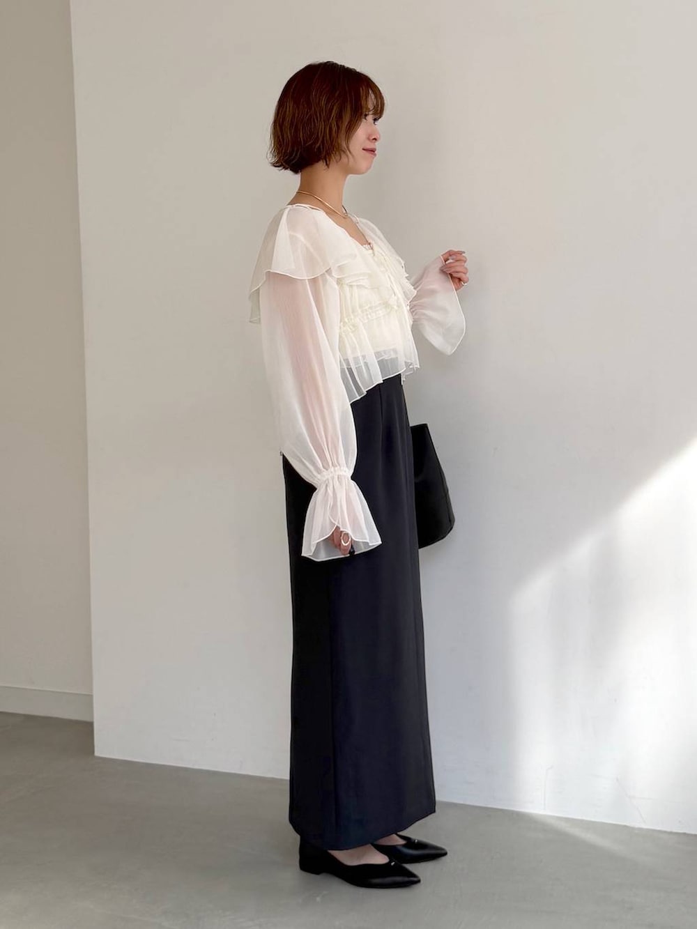 ブラック系のパンプス、ホワイト系のシャツ/ブラウス、ブルー系のスカートを着用したレディースの春コーディネートの2枚目の写真