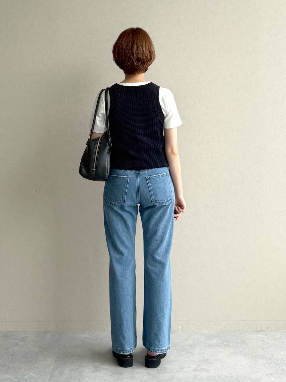 ブラック系のハンドバッグ、ブルー系のデニムパンツ、ブラック系のサンダルを着用したレディースの夏コーディネートの3枚目の写真