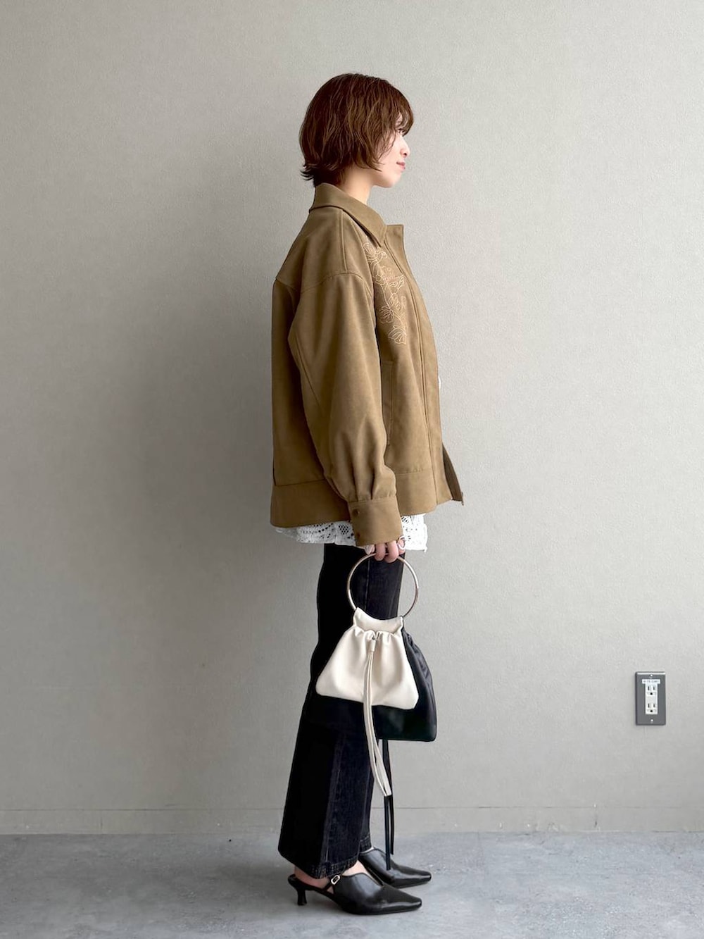 ブラック系のデニムパンツ、ブラック系のサンダル、ブラウン系のブルゾンを着用したレディースの冬コーディネートの2枚目の写真