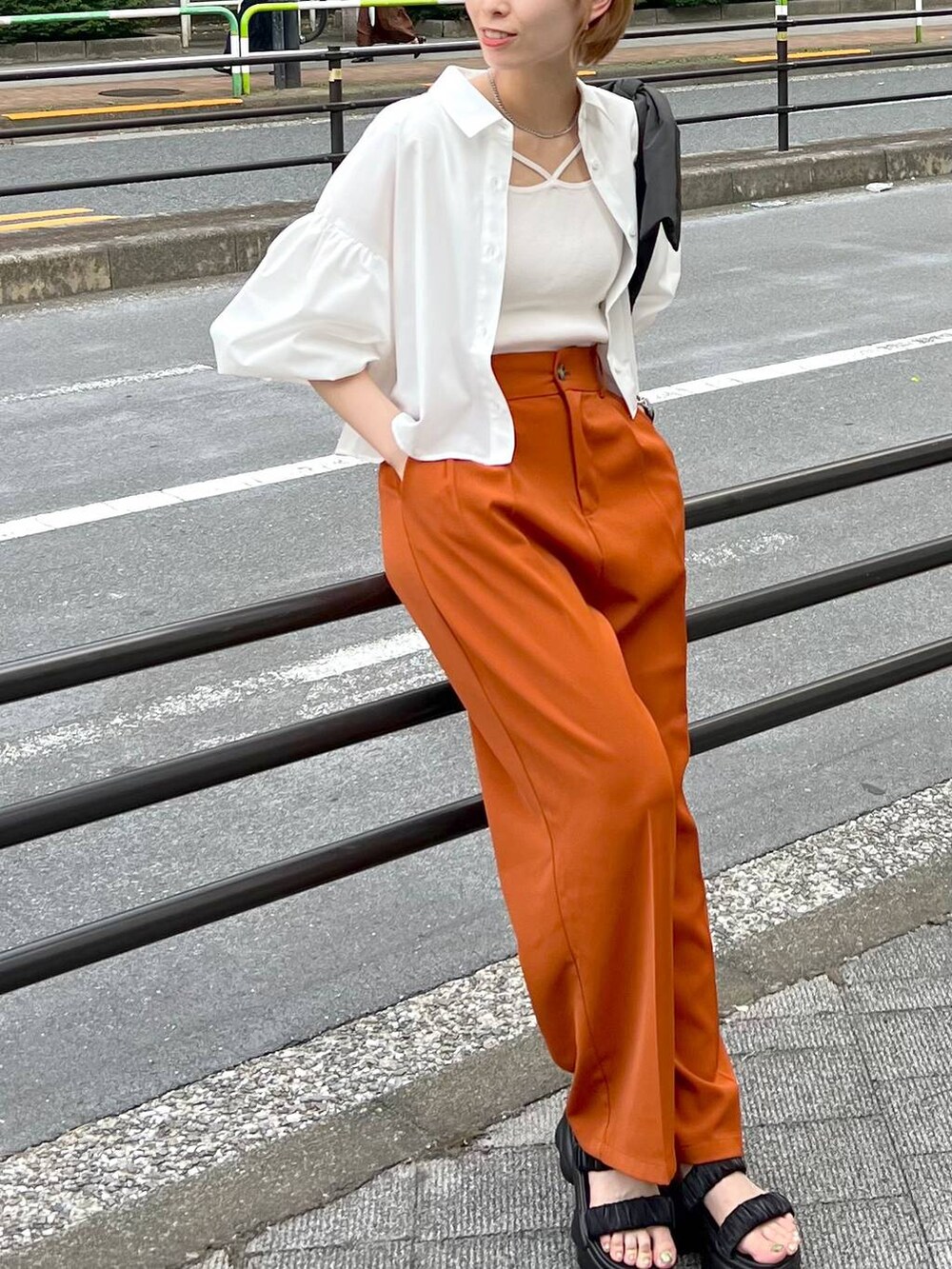 ブラック系のショルダーバッグ、ホワイト系のシャツ/ブラウス、オレンジ系のスラックスを着用したレディースの秋コーディネートの6枚目の写真