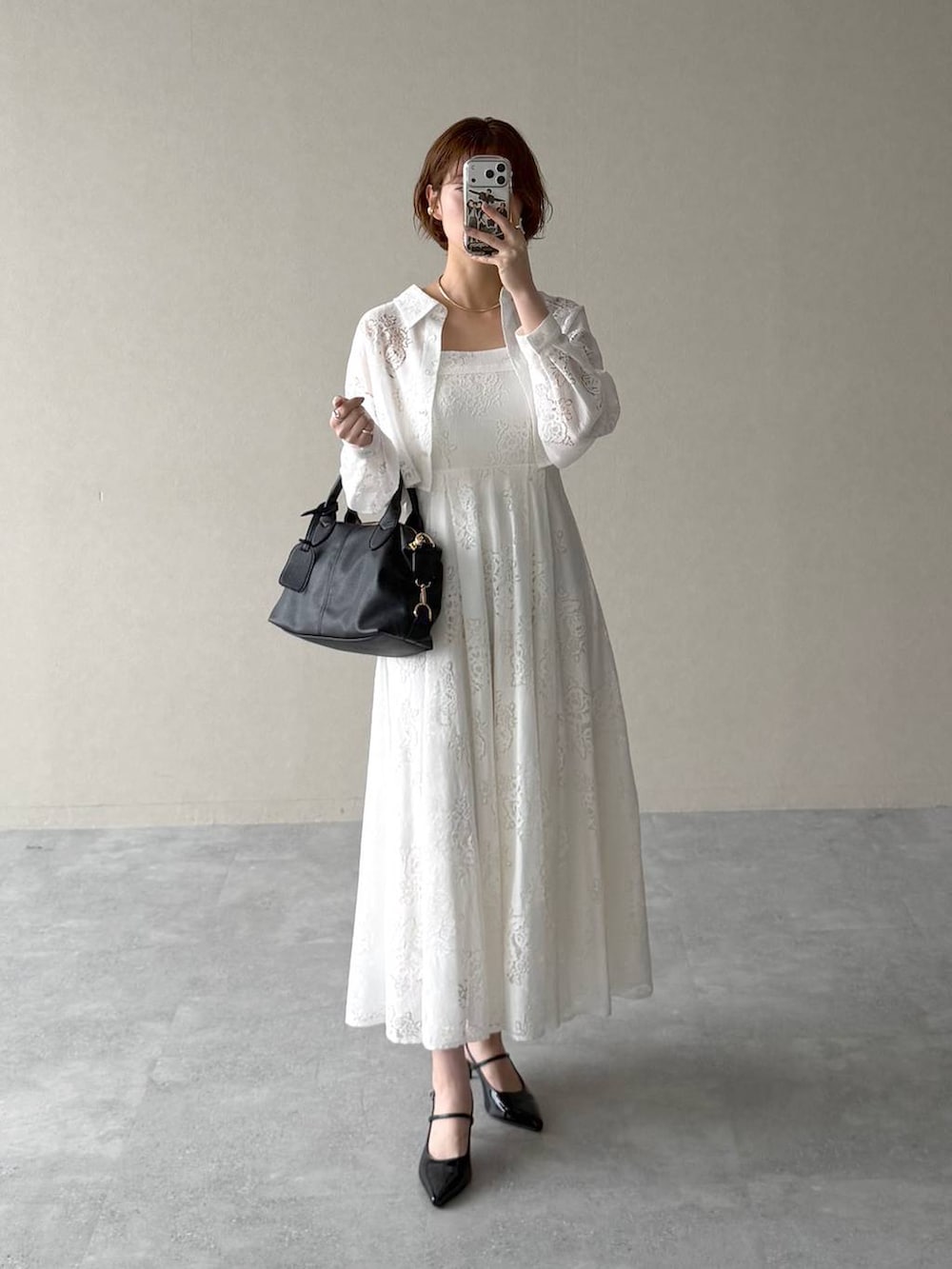 ブラック系のボストンバッグ、ブラック系のサンダル、ホワイト系のワンピースを着用したレディースの春コーディネートの6枚目の写真