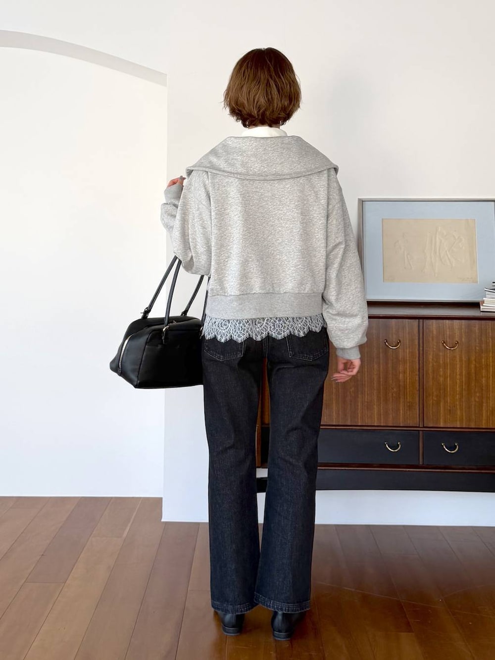 ブラック系のハンドバッグ、ブラック系のデニムパンツ、ブラック系のパンプスを着用したレディースの冬コーディネートの3枚目の写真