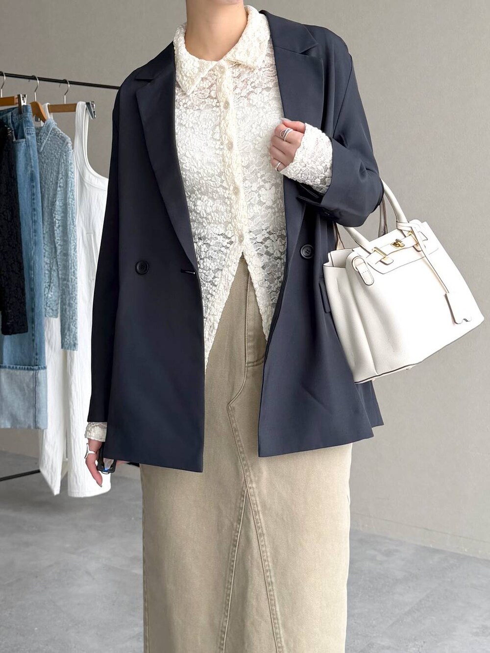 ブラック系のサンダル、ブルー系のテーラードジャケット、ベージュ系のスカートを着用したレディースの春コーディネートの7枚目の写真