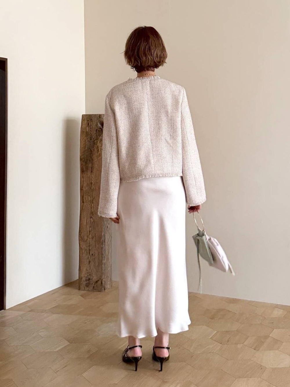 ブラック系のサンダル、ホワイト系のノーカラージャケット、ホワイト系のスカートを着用したレディースの冬コーディネートの3枚目の写真