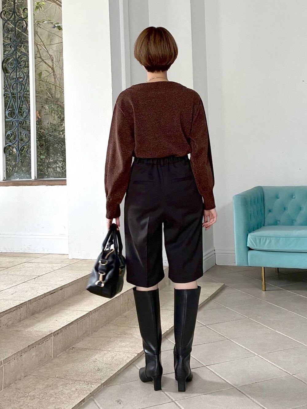 ブラウン系のニット/セーター、ブラック系のボストンバッグ、ブラック系のブーツを着用したレディースの冬コーディネートの6枚目の写真