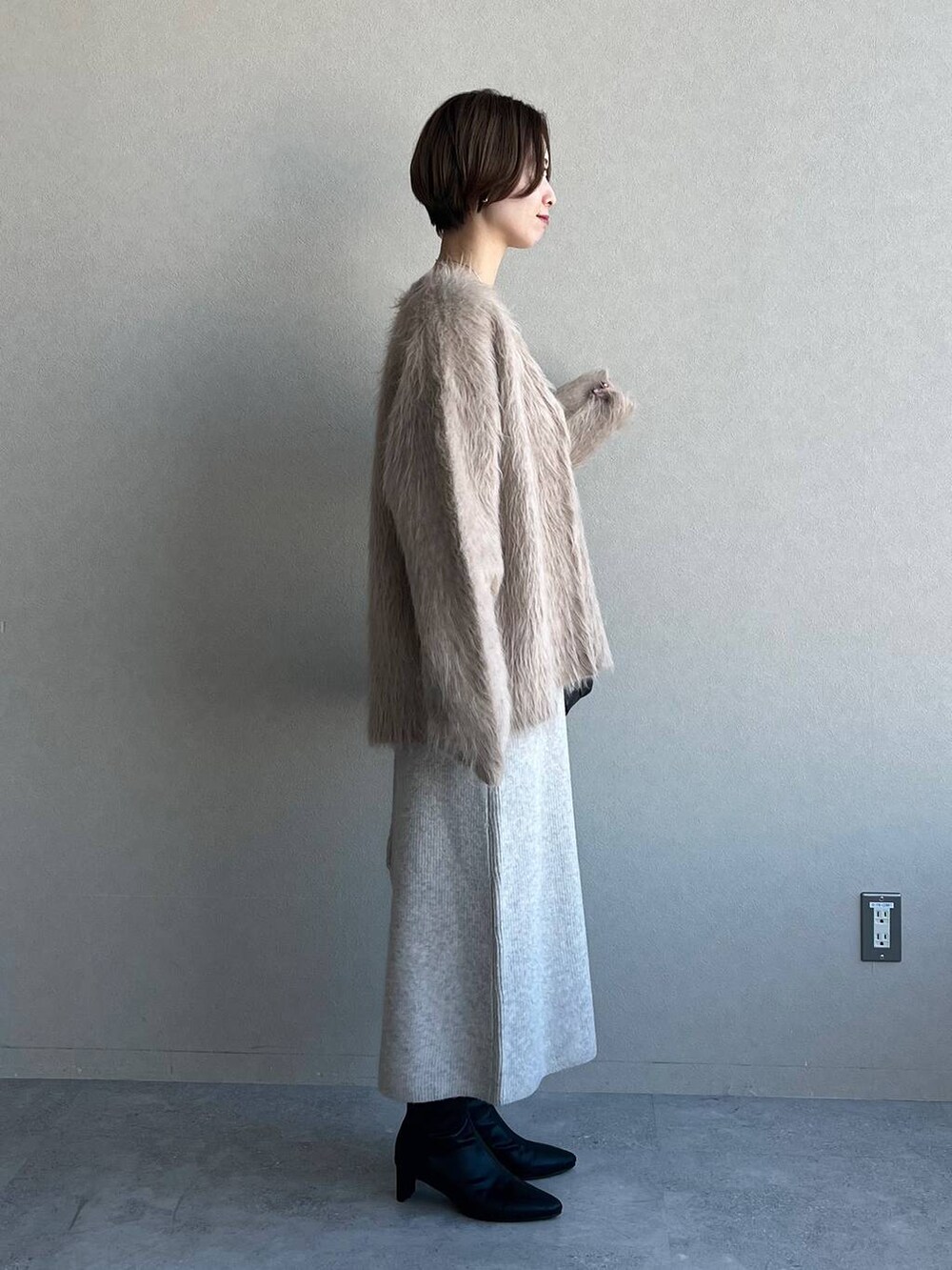 ブラック系のハンドバッグ、ブラック系のブーツ、ベージュ系のカーディガン/ボレロを着用したレディースの冬コーディネートの2枚目の写真