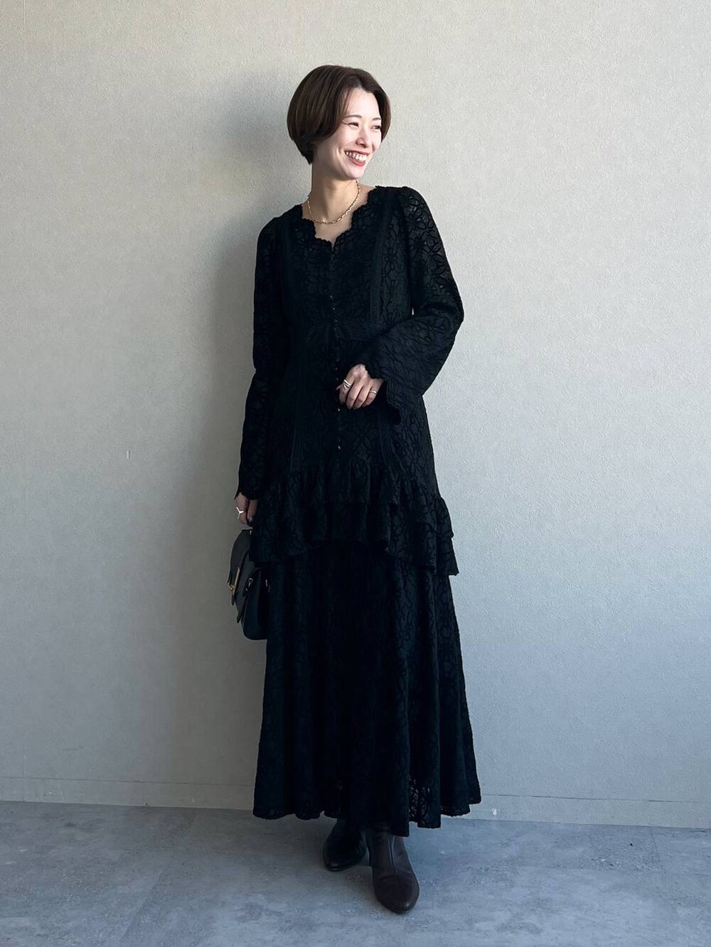 ブラック系のワンピース、パープル系のチェスターコート、ブラック系のブーツを着用したレディースの冬コーディネートの4枚目の写真