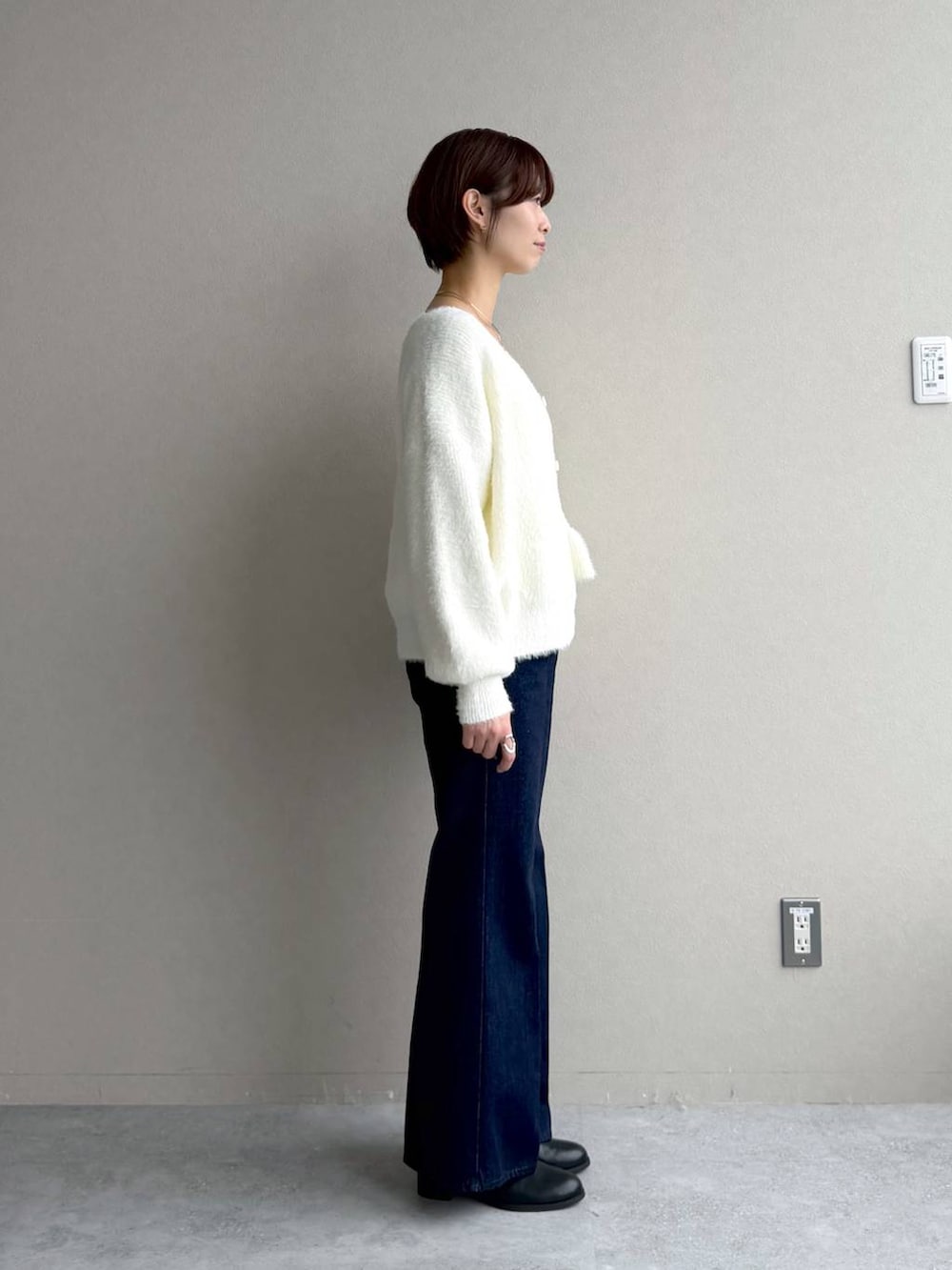 ブルー系のデニムパンツ、ホワイト系のカーディガン/ボレロ、ブラック系のボストンバッグを着用したレディースの秋コーディネートの6枚目の写真